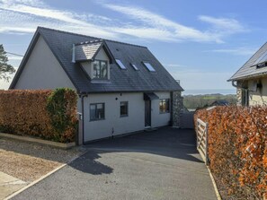 A two-story house with a sloped roof, a driveway, and a view of the sea. - Luxury Whitby Townhouse for 10 (Dyffryn Ardudwy)