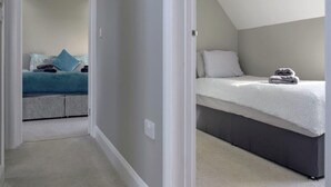 A bedroom with a bunk bed, a single bed, and a carpeted floor. - Luxury Whitby Townhouse for 10 (Dyffryn Ardudwy)
