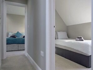 A bedroom with a bunk bed, a single bed, and a carpeted floor. - Luxury Whitby Townhouse for 10 (Dyffryn Ardudwy)