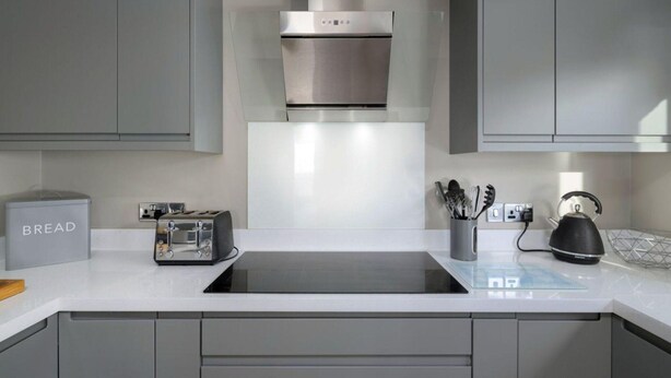 A modern kitchen with grey cabinets, a stainless steel range hood, a toaster, and a kettle on the counter. - Luxury Whitby Townhouse for 10 (Dyffryn Ardudwy)