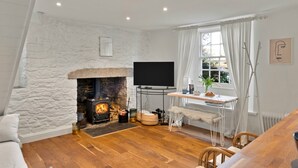 Una sala de estar acogedora con chimenea de piedra, televisor de pantalla plana y un comedor con mesa y sillas.
