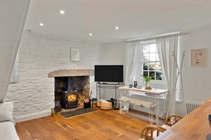 Una sala de estar acogedora con chimenea de piedra, televisor de pantalla plana y un comedor con mesa y sillas.
