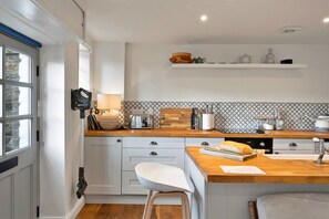 Une cuisine moderne avec un plan de travail en bois, des meubles blancs et un four encastré.