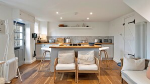 Cocina funcional con una isla central, sillas de madera y un sofá blanco.