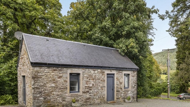 Un cottage in pietra con tetto spiovente, una porta e una piccola finestra.
