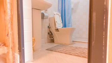 Un baño con inodoro, ducha y un tapete en el suelo.