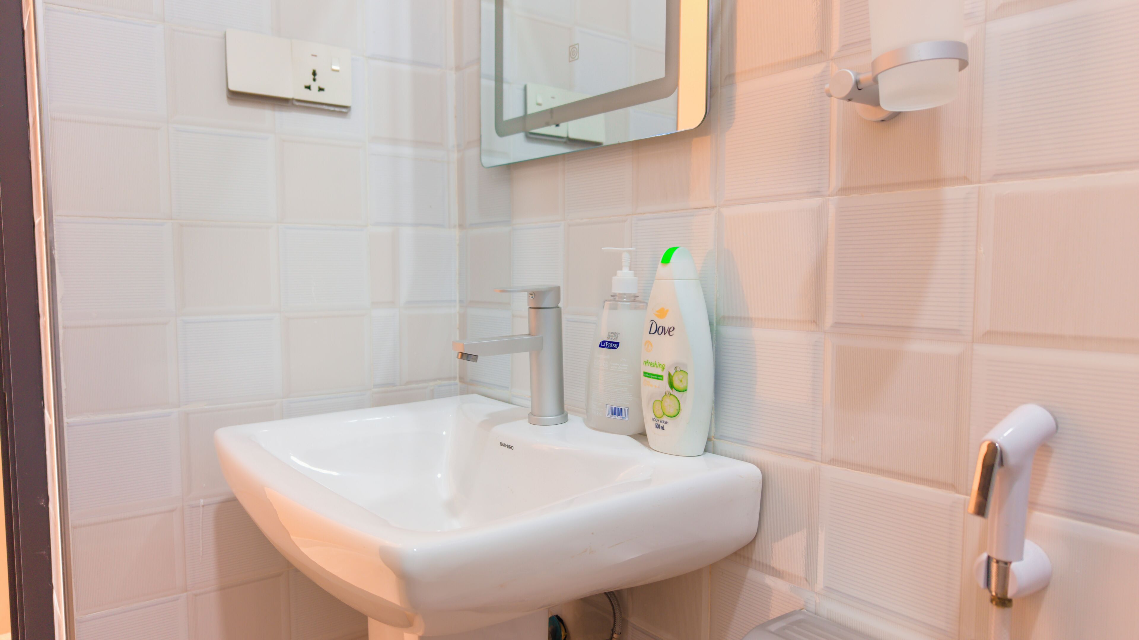 Une salle de bain avec un lavabo blanc, un miroir et un savon Dove.