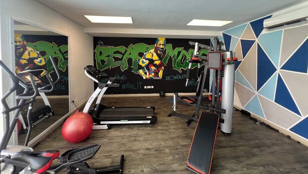 A gym with exercise equipment, a red exercise ball, and a motivational mural on the wall. - Stylish East Legon 1BR | Pool & Gym (Accra)