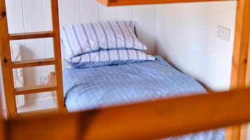 Una cama litera con colcha azul a cuadros y almohadas a rayas.