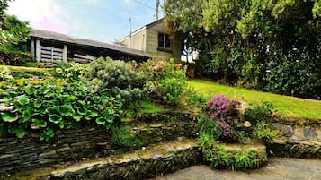 Un muro de piedra con una escalera de piedra que sube hacia una casa con cerca de madera.