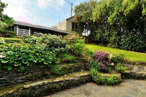 Un muro de piedra con una escalera de piedra que sube hacia una casa con cerca de madera.
