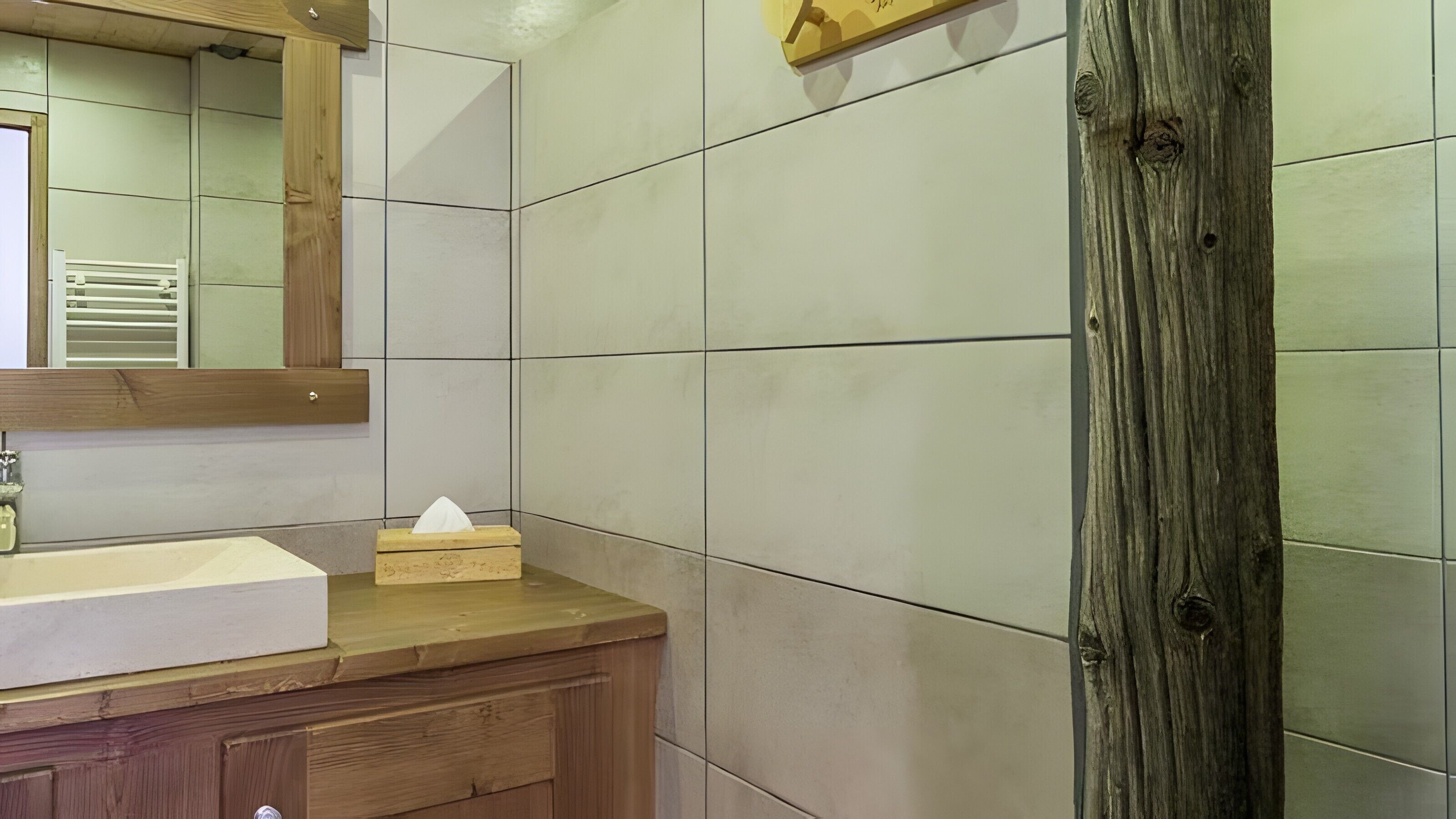 A bathroom with a wooden vanity, a mirror, and a wooden column.