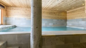 Un área de spa con piscina de mosaicos de piedra y techo de madera.