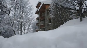 A snow-covered building with multiple balconies, surrounded by trees. - “Chalet Le Névé - Le Tétras-Lyre” with Mountain View, Heated Pool, 150m from the Slopes (Bonneval-sur-Arc)