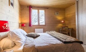 Une pièce en bois avec un lit, une fenêtre, un radiateur et une chaise.