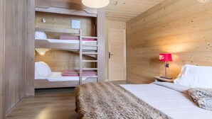 Una habitación de madera con literas, una mesita de noche con lámpara y un ventanal grande.