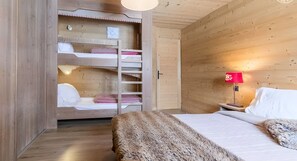 Ein Zimmer mit Holzboden, einem Etagenbett, einem Nachttisch mit Lampe und einem großen Fenster.