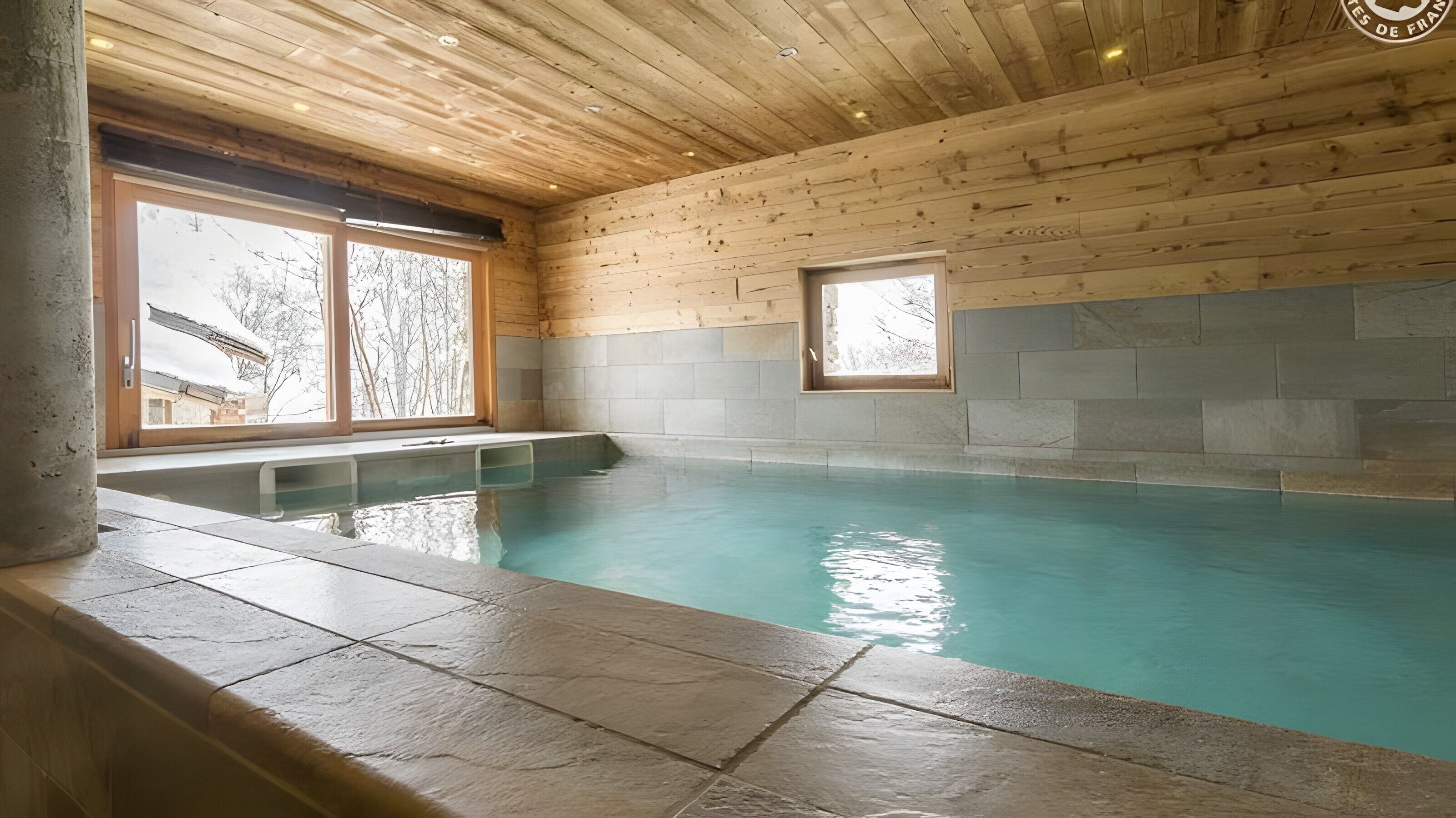 An indoor swimming pool with wooden walls and a stone floor.