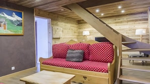 Interior de una cabaña de madera con sofá, una mesa y un cuadro en la pared.