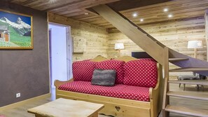 Ein gemütliches Holzblockhaus-Interieur mit einer Couch, einem Tisch und einem Bild an der Wand.