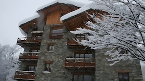 Ein mehrstöckiges Steinhaus mit hölzernen Balkonen und verschneiter Umgebung.