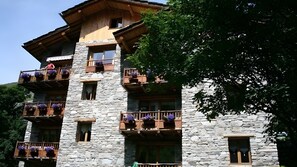 Ein mehrstöckiges Steinhaus mit Balkonen, auf denen Kübelpflanzen stehen.