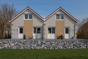 A two-story residential building with a symmetrical facade, a stone foundation, and a red-tiled roof. - Deluxe Comfy Waterfront Bungalow (Makkum)