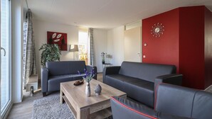 Ein modernes Wohnzimmer mit zwei Sofas, einem Couchtisch und einer roten Akzentwand.