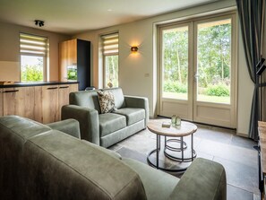 A modern living room with a sofa, a coffee table, and a kitchen area with a window. - Farmhouse Near De Koog (De Koog)