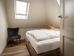 Una camera da letto con un letto, una sedia, una finestra e una porta.