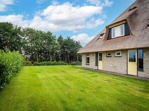 Ein Haus mit einem geneigten Dach, einem gepflegten Rasen und blauem Himmel.