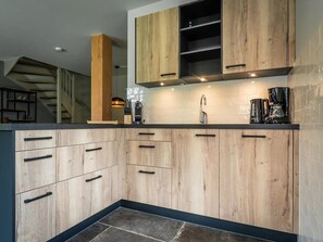 Eine moderne Küche mit Holzschränken, einer Edelstahl-Spüle und einer Kaffeemaschine.
