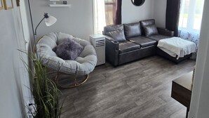Ett modernt vardagsrum med en grå soffa, ett runt soffbord och en golvlampa.