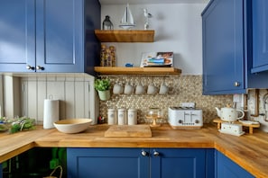 Eine Küche mit blauen Schränken, einer Holz Arbeitsplatte, einem Toaster und einer abgehängten Küchenutensilienstange.