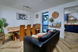 Una sala de estar moderna con comedor, un sofá de cuero negro, una mesa de comedor de madera y sillas.