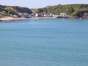 Une ville côtière avec des bâtiments qui bordent la plage, une étendue de sable et des eaux bleues et calmes.