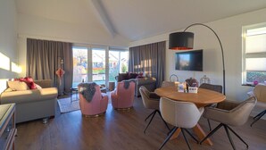 Een moderne woonkamer met een bank, stoelen, een eettafel en een televisie.