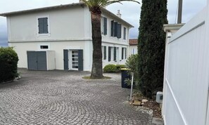 A white building with a cobblestone driveway, a palm tree, and a hedge. - A PERFECT BLEND OF LUXURY WITH BREATHTAKING 360° VIEWS MEDITERRANEAN SEA (Cannes)