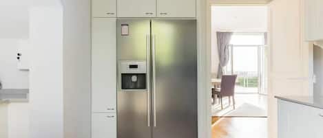 Une cuisine moderne équipée d’un réfrigérateur en acier inoxydable, d’un four encastré et d’un distributeur d’eau.