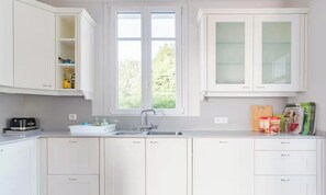 A modern kitchen with white cabinets, a built-in sink, and a window providing natural light. - A PERFECT BLEND OF LUXURY WITH BREATHTAKING 360° VIEWS MEDITERRANEAN SEA (Cannes)
