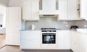 Eine moderne Küche mit weißen Schränken, einem eingebauten Backofen und einem Gasherd.