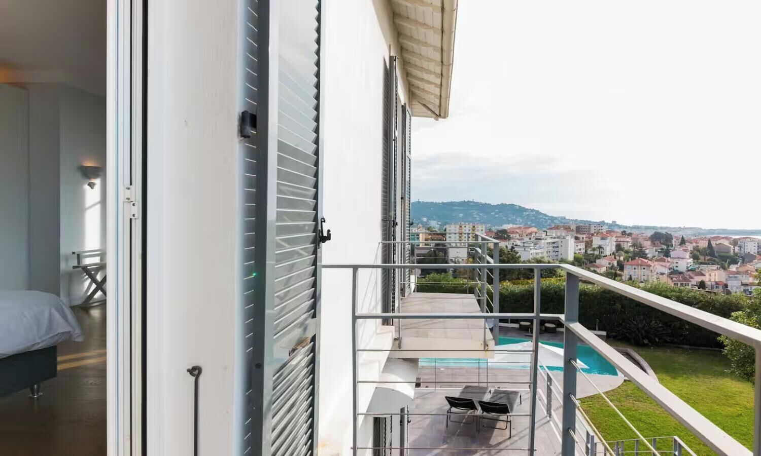A balcony with a pool, a bed, and a city view.