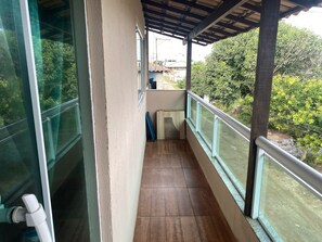 A balcony with a view of greenery and a building in the background.