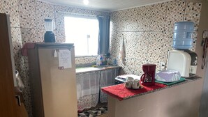 Ett kök med kylskåp, vattenautomat, kaffebryggare och diskho.
