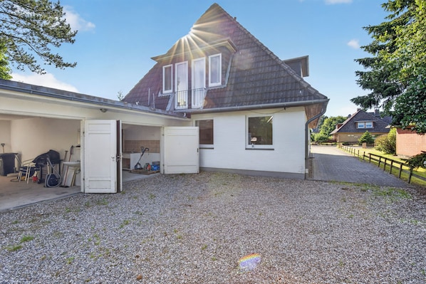 A two-story house with a gravel driveway, a garage, and a small attached shed. - Amselnest St. Peter-Ording for up to 8 people (Sankt Peter-Ording)