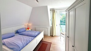 Un dormitorio con cama, mesita de noche, radiador y vistas al exterior.