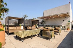 An outdoor seating area with cushioned chairs and a sofa, a pergola, and a view of a cityscape. - Charming 1-bedroom apartment in the heart of Interlomas (Naucalpan de Juárez)