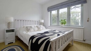 A bedroom with a bed, bedside tables, a window with a view, and a rug. - Stylish Barn Retreat for 8 (Pwllheli)