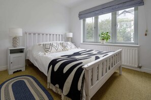 Ein Schlafzimmer mit einem Bett, Nachttischen, einem Fenster mit Blick und einem Teppich.