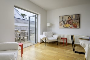 A modern living room with a sofa, chairs, a dining table, and a painting on the wall. - Stylish Barn Retreat for 8 (Pwllheli)